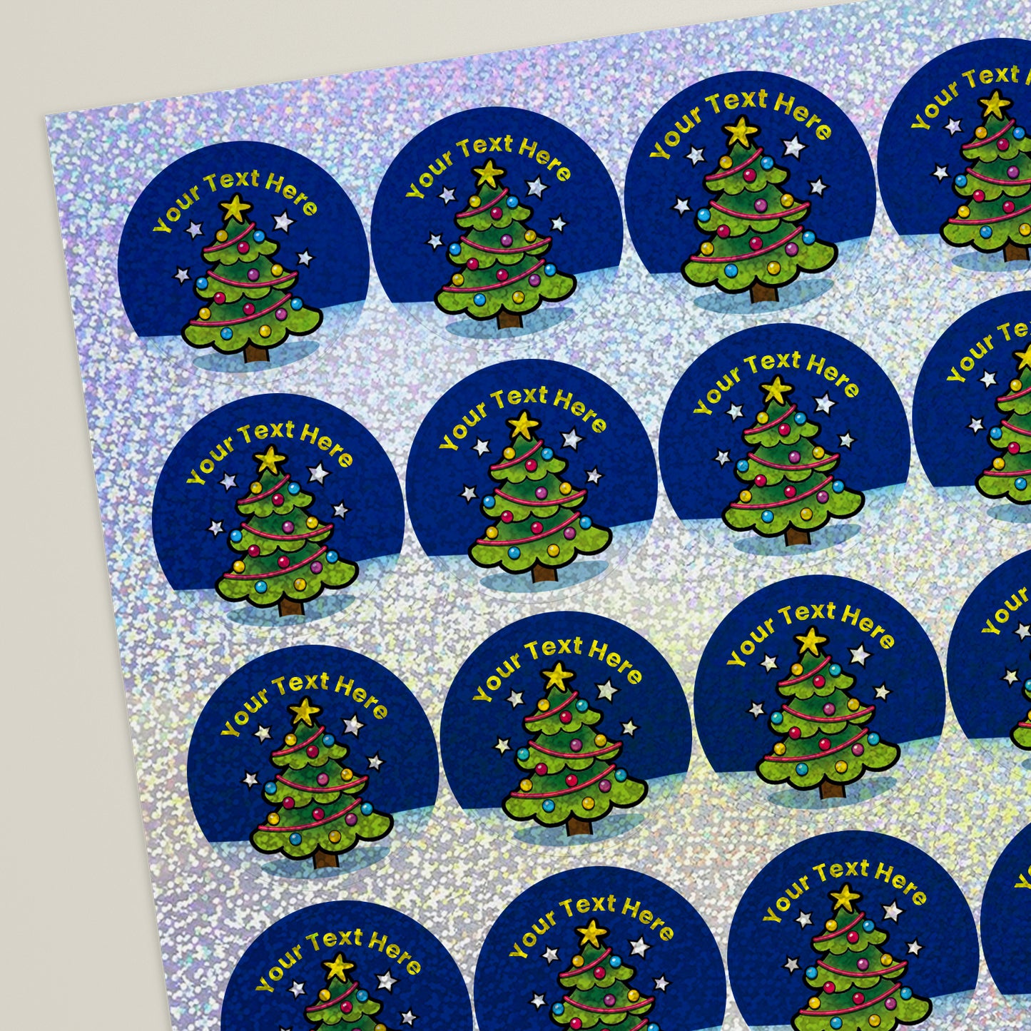 A sheet of personalised holographic Christmas tree stickers with a blue background and multicoloured lights.
