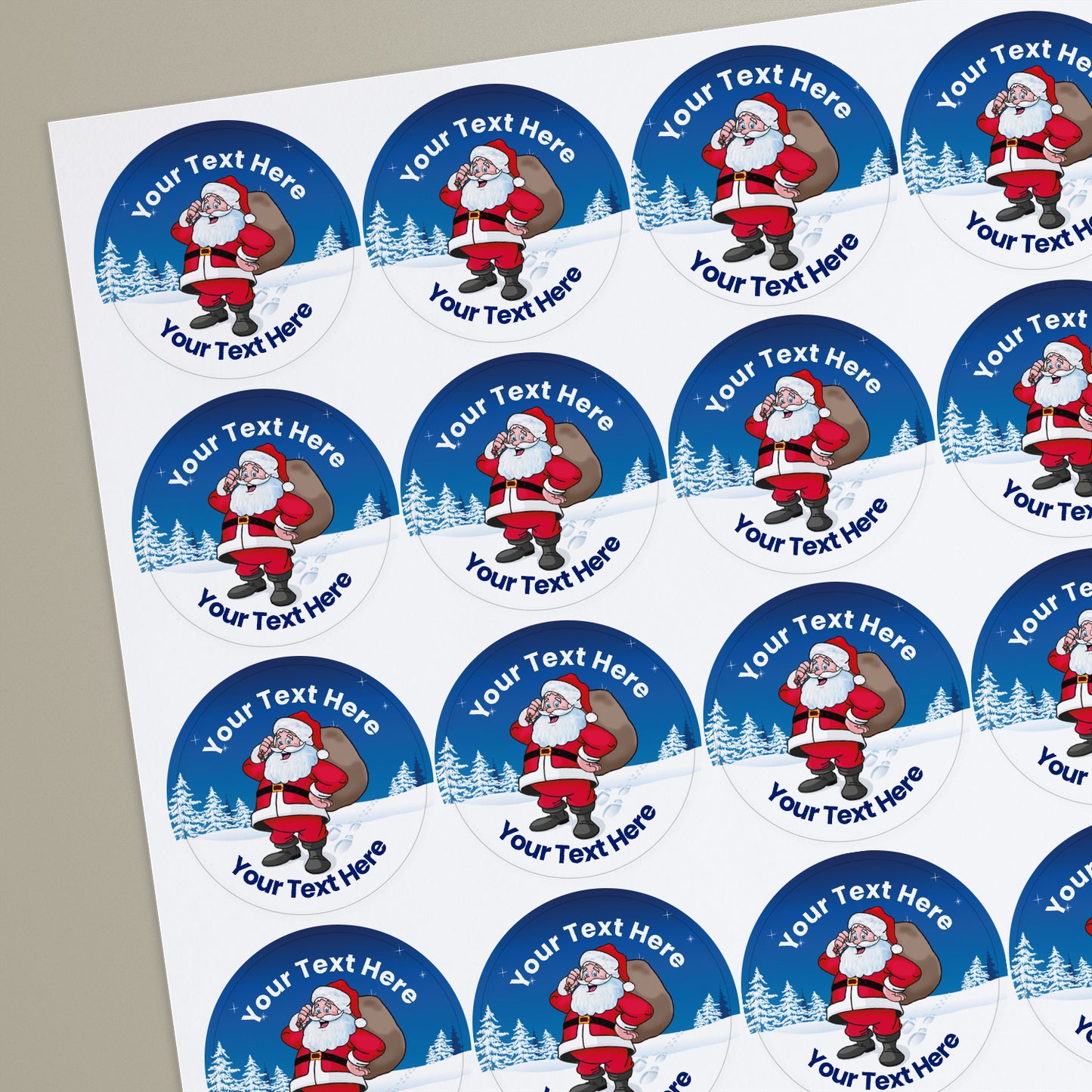 A sheet of customisable circular stickers featuring a cheerful Father Christmas holding a sack of presents set against a snowy blue background with pine trees; includes customisable text above and below Santa.