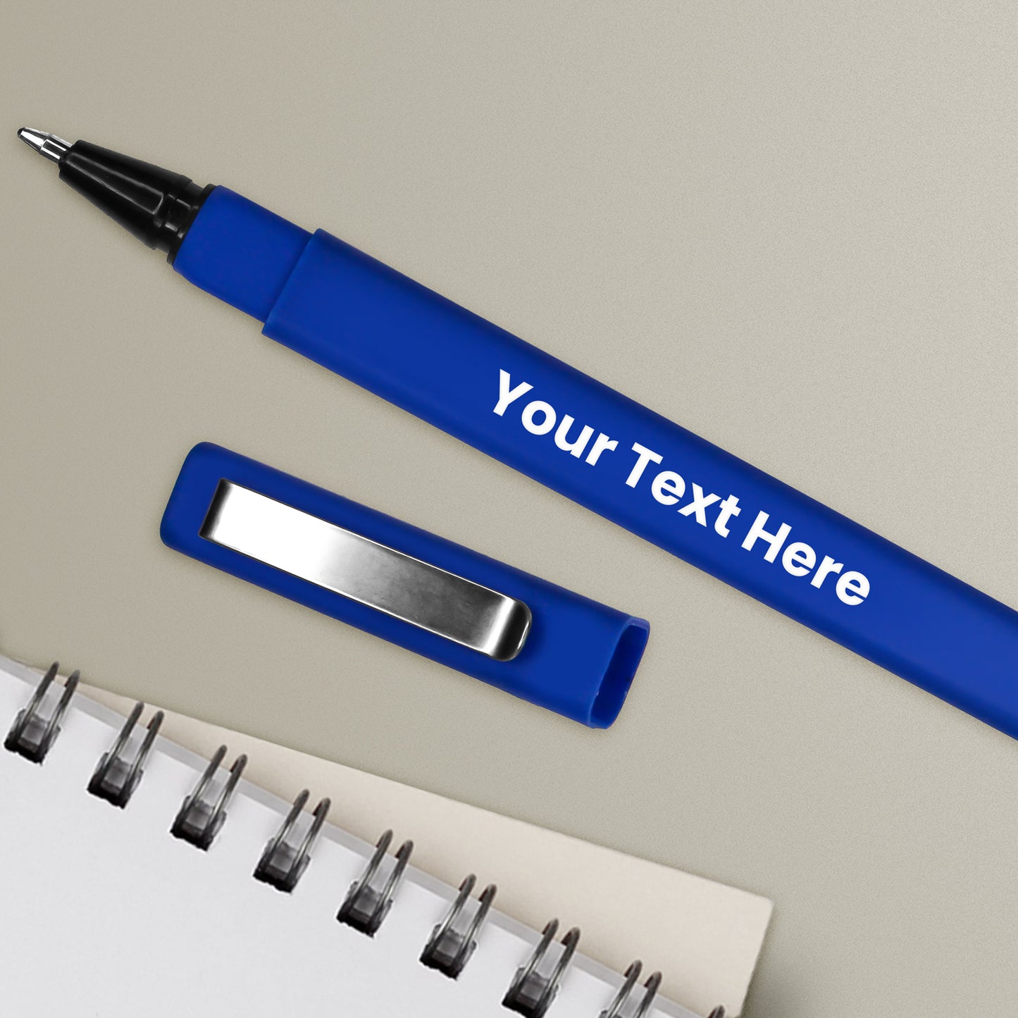 A personalised royal blue pen with a black ink cartridge, a brushed metal clip, and a space for custom text positioning, alongside a notepad and a pen loop.