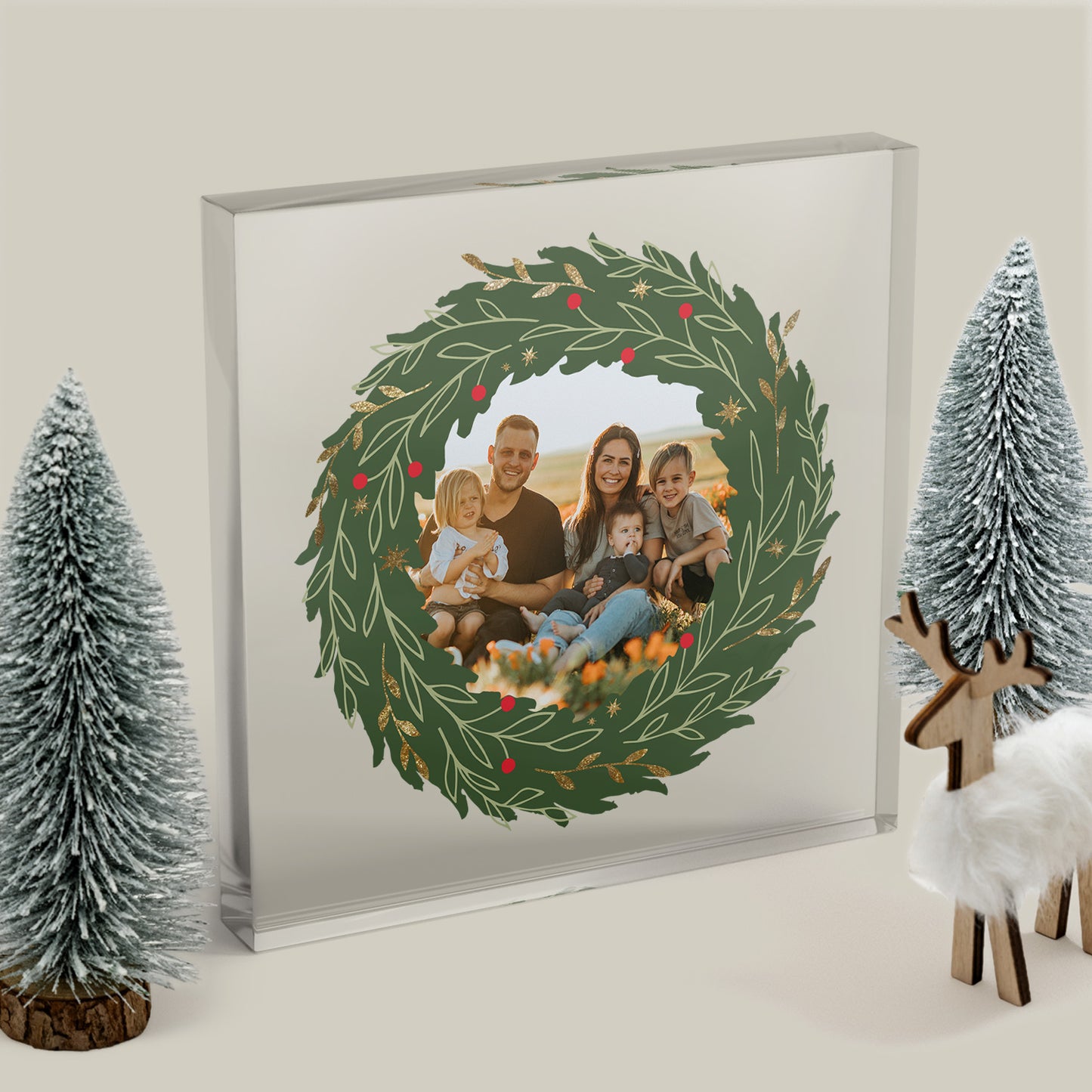Framed family photo with a Christmas wreath design, surrounded by decorative trees and a deer.