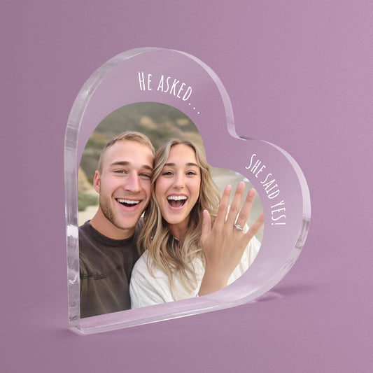 Heart-shaped acrylic photo block with a couple's picture and 'He Asked... She Said Yes!' text on a pink background.
