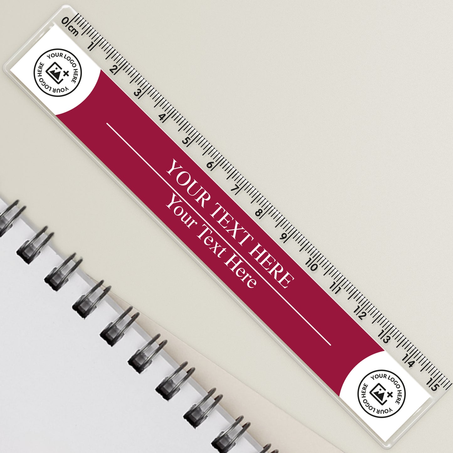 A personalised ruler with a maroon background and white text, featuring a placeholder for a custom photo or logo, resting on a spiral-bound notebook with a pen.