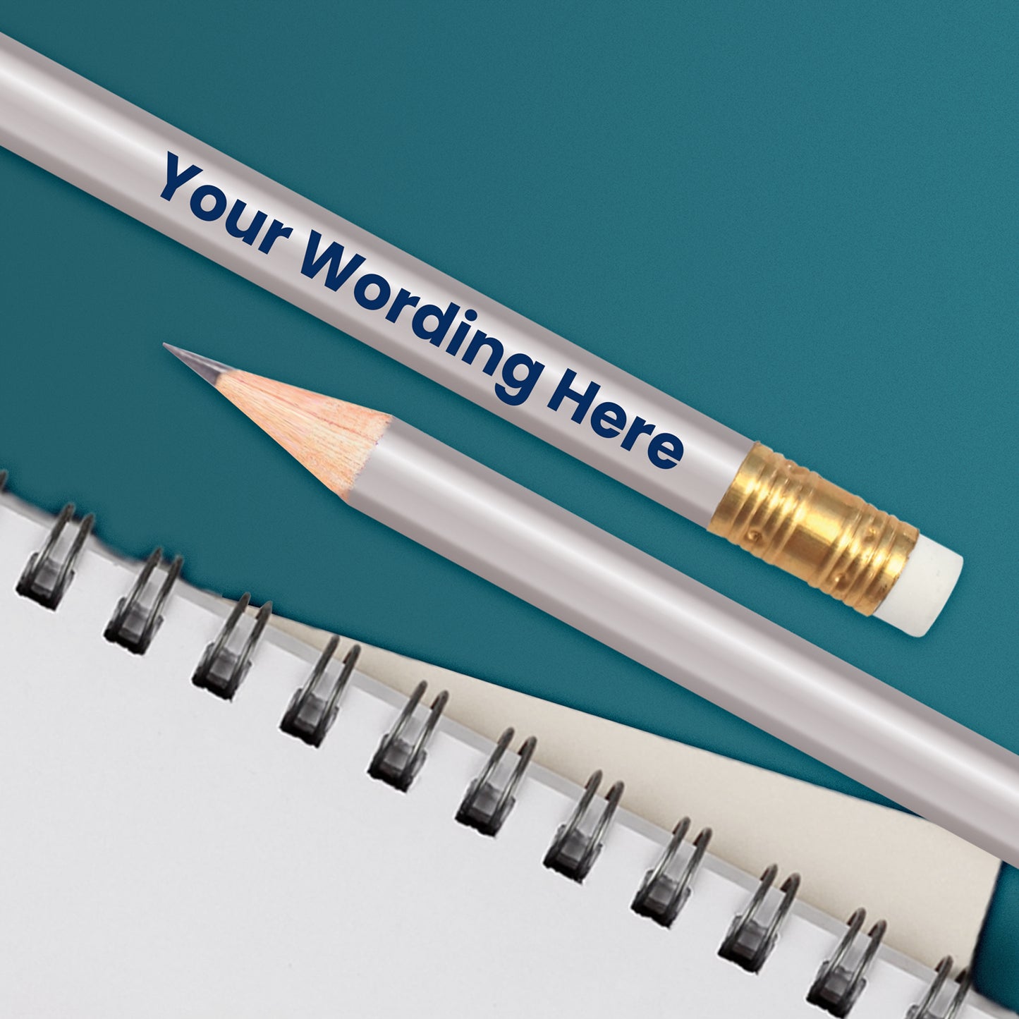 A silver HB pencil with customised text 'Your Wording Here' printed on it, positioned next to a notepad with dotted lines.