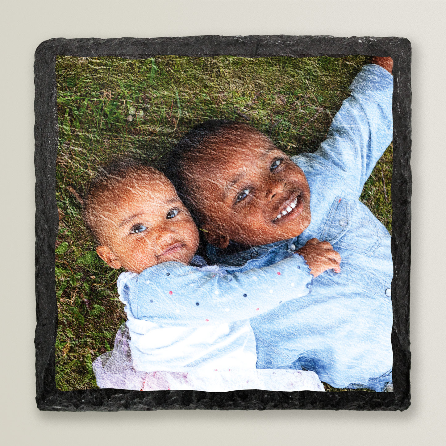 Photo of two children hugging on grass printed onto a natural-finish slate coaster.