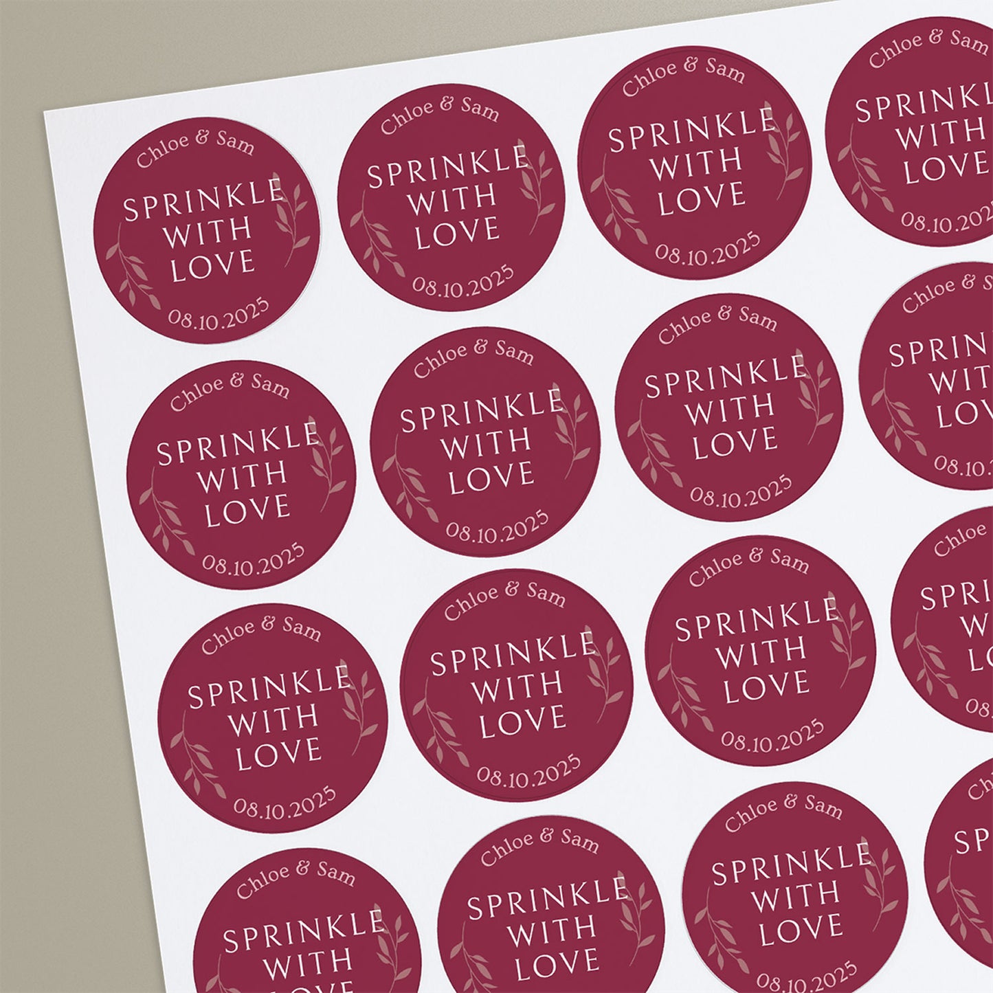A sheet of round, red confetti cone stickers with white text 'Chloe & Sam SPRINKLE WITH LOVE' and a date '08.09.2025' beneath the text.