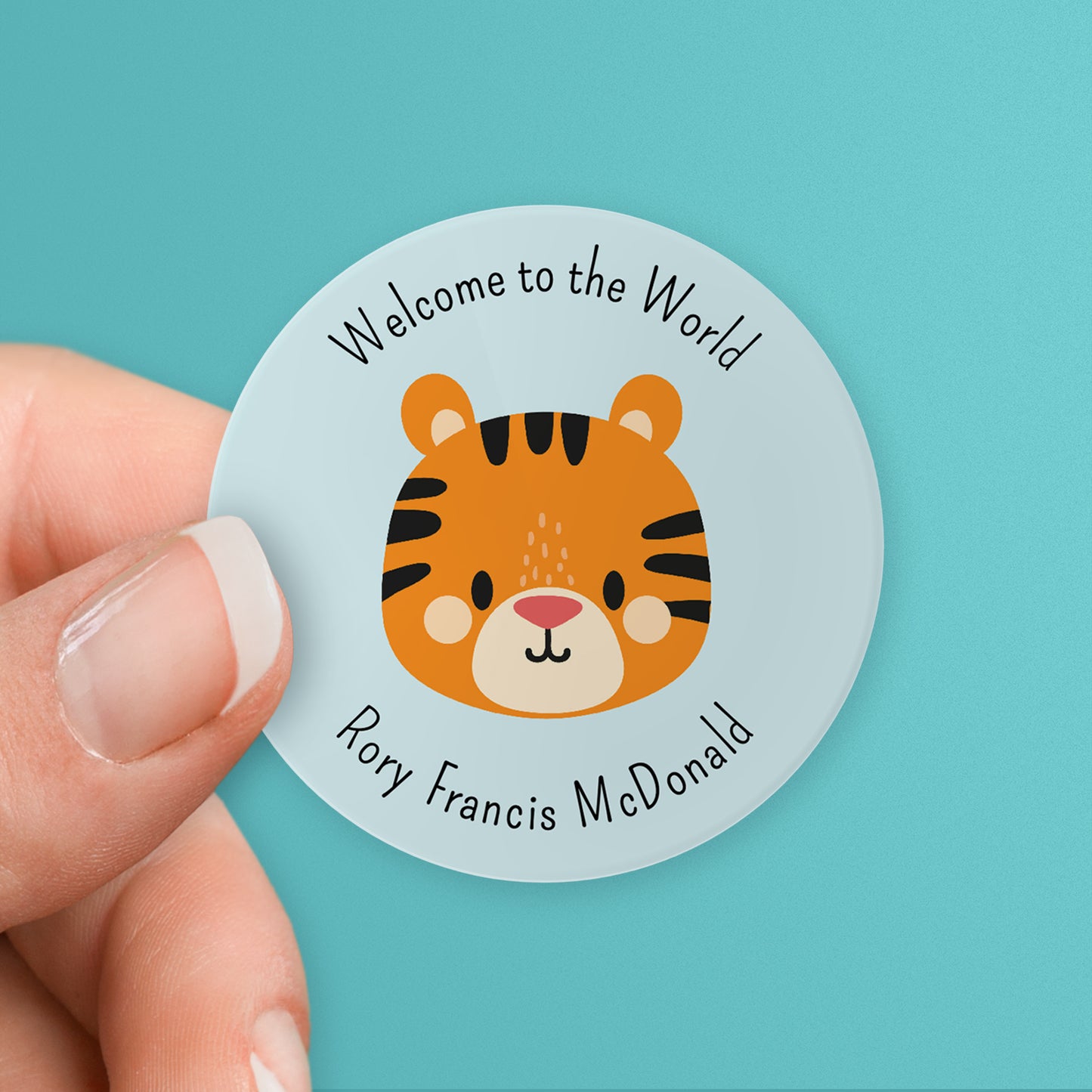 A hand holding a round sticker with a tiger central and customisable text space for personalisation.