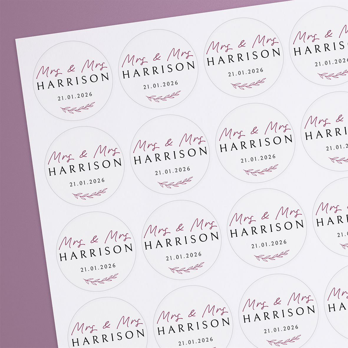 A sheet of round, white stickers with personalized text and a floral design in dusky pink.