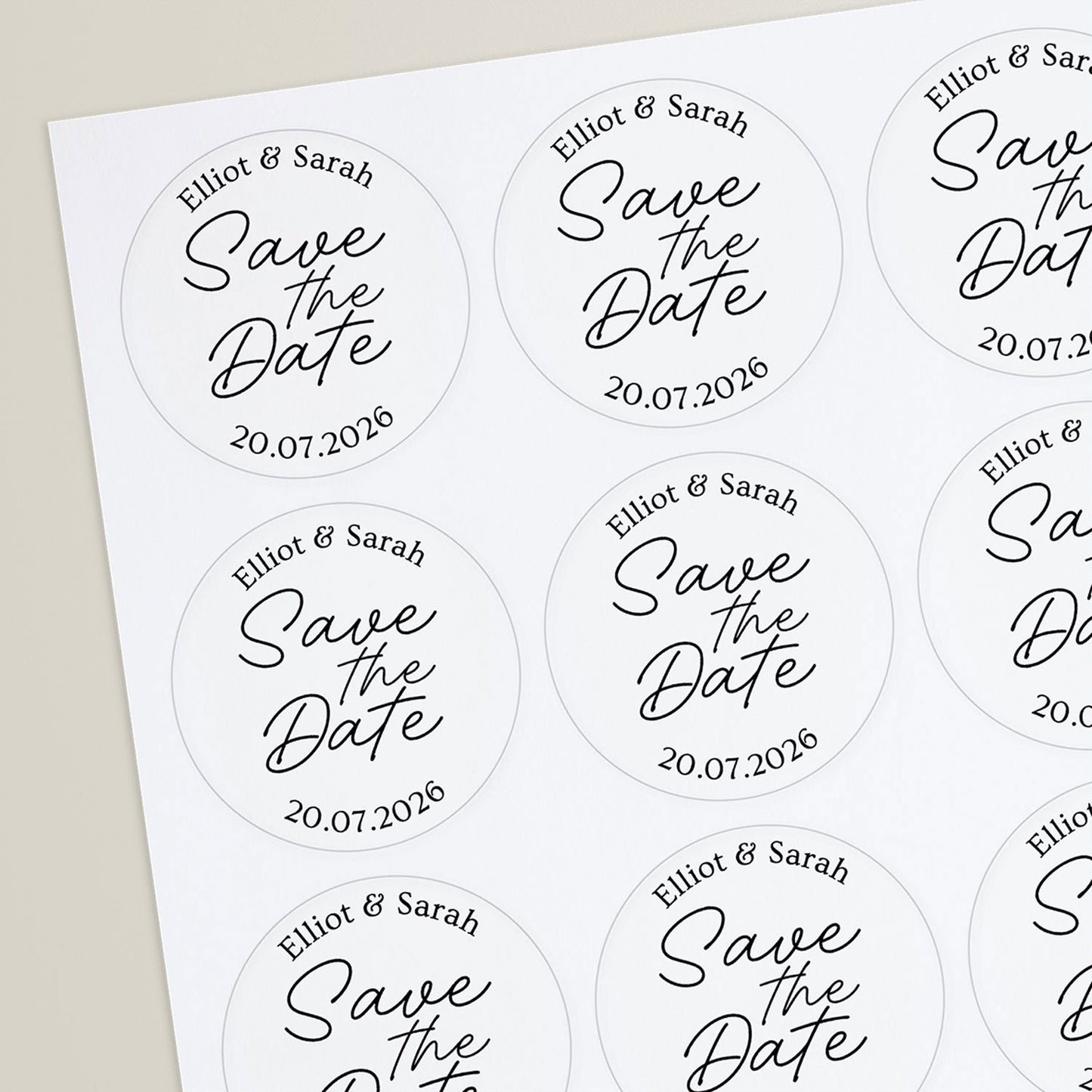 A hand holding a round, white 'Save the Date' sticker with custom text
