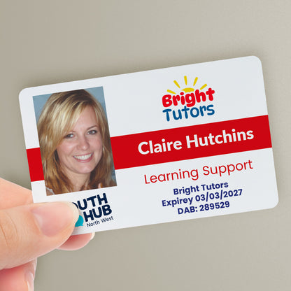 A personalised tutor ID card with a photo, company logo, trust logo, and custom text. The ID card is held in a hand and has a red colour strip - with the name 'Claire Hutchins' and the title 'Learning Support'.