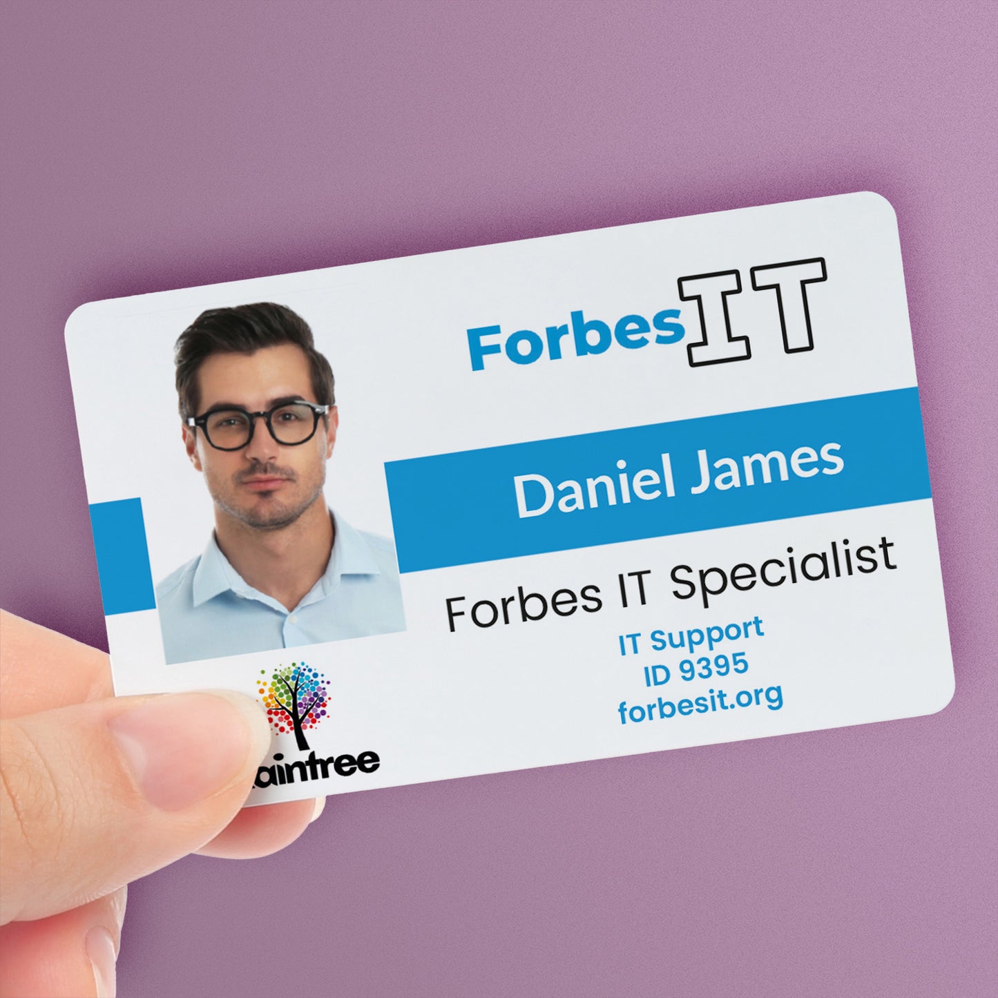 A personalised IT ID card with a photo, company division logo, main logo, and custom text. The ID card is held in a hand and has a blue colour strip - with the name 'Daniel James' and the title 'Forbes ID Specialist'.