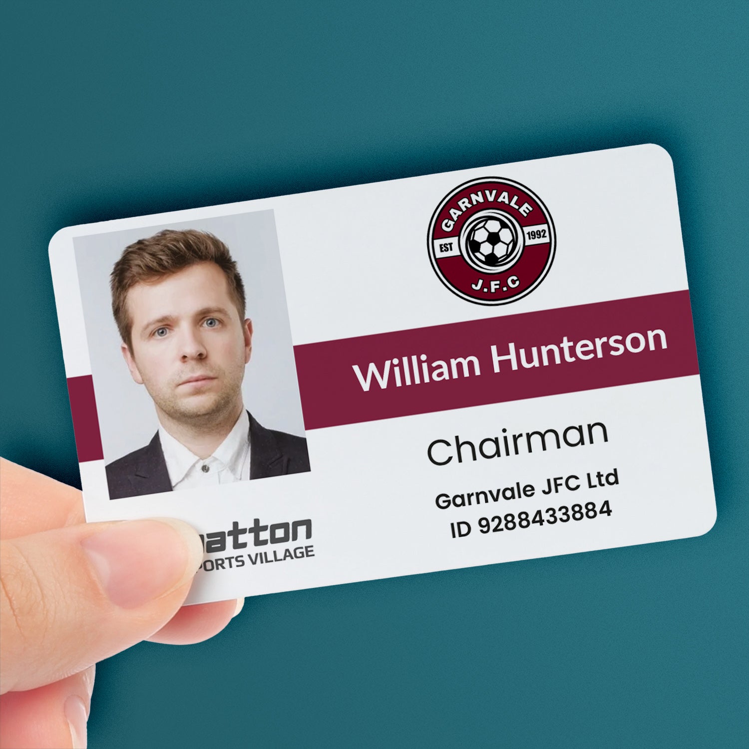 A personalised ID card with a photo, company logo, local authority logo, and custom text. The ID card is held in a hand and has a maroon colour strip - with the name 'Williams Hunterson' and the title 'Chairman'.