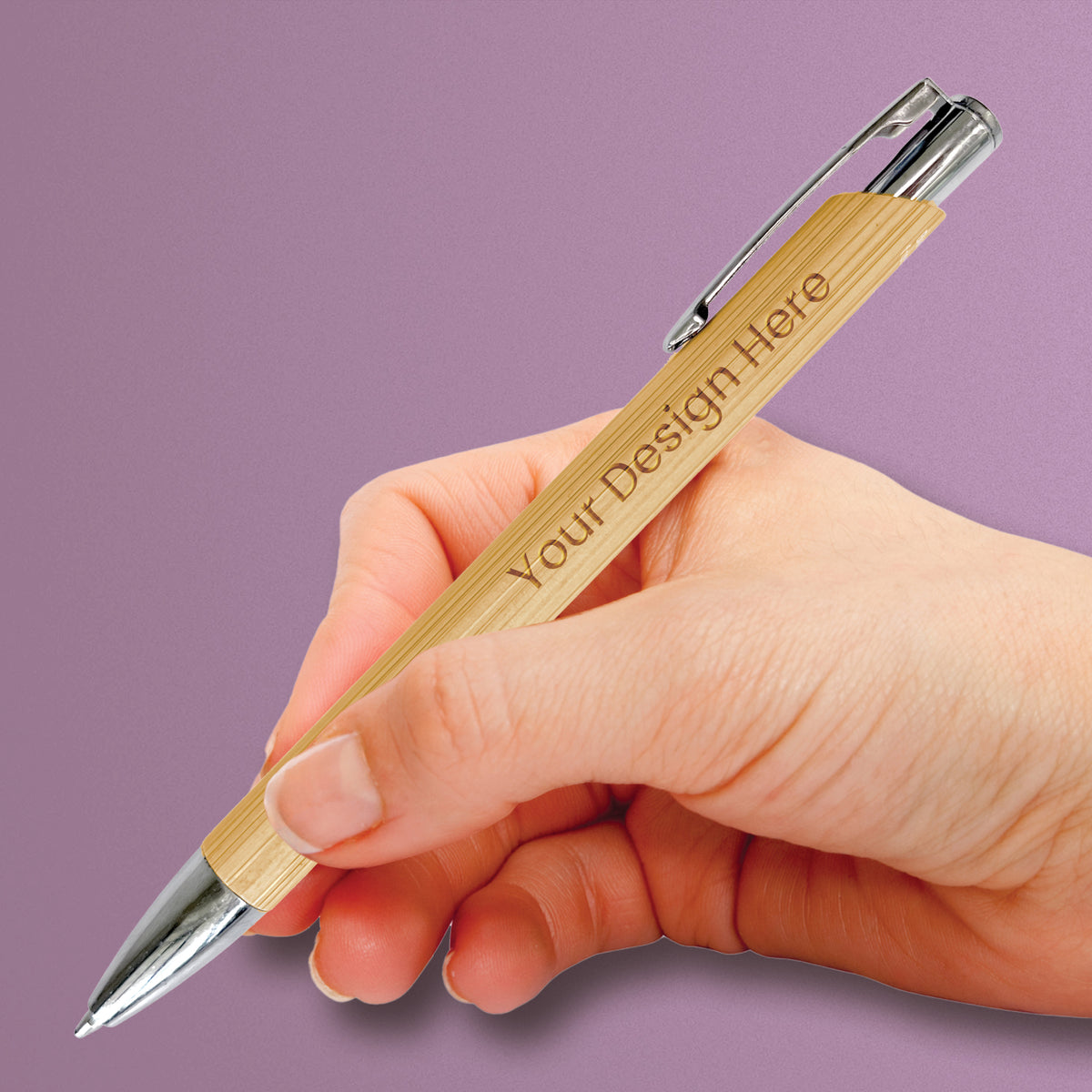 Hand holding a personalised bamboo ballpoint pen, showing its comfortable shape, engraved design and silver-tone detailing.