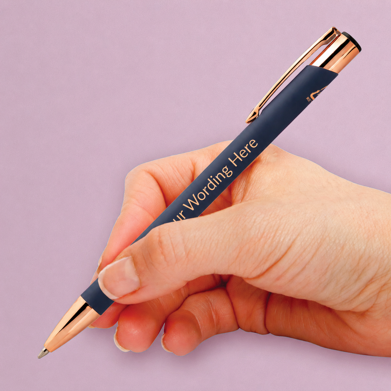 Navy personalised pen with rose gold detailing and engraved wording, shown being held in the hand.