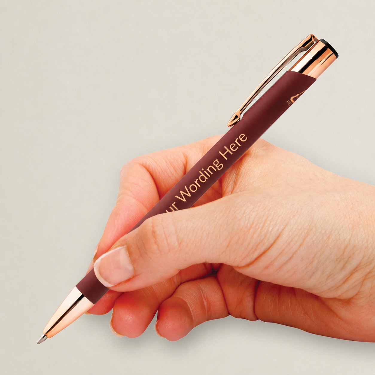 Burgundy personalised pen with rose gold detailing and engraved wording, shown being held in the hand.