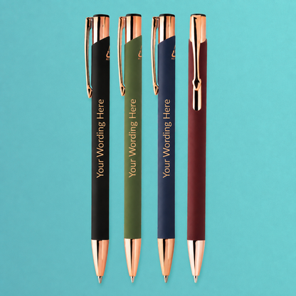 Personalised pens in black, green, navy and burgundy with rose gold trim, displayed upright on a teal background.