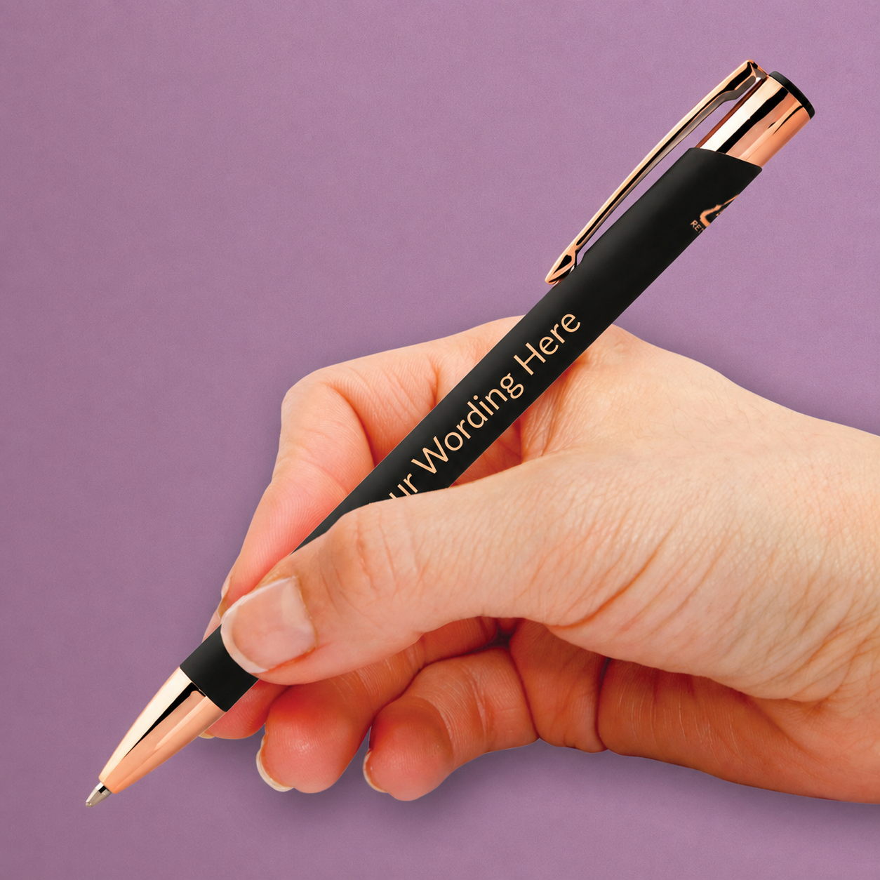 Black personalised pen with rose gold detailing and engraved wording, shown being held in the hand.
