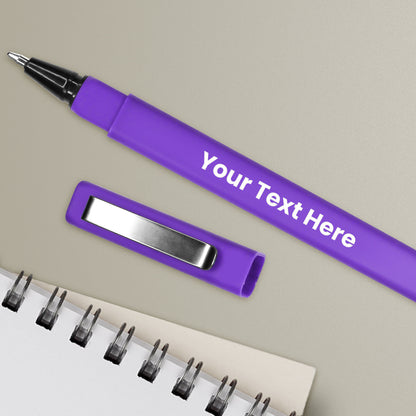 A personalised lilac pen with a black ink cartridge, a brushed metal clip, and a space for custom text positioning, alongside a notepad and a pen loop.
