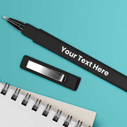 A personalised black pen with a ball point nib and a brushed metal clip, placed on a notebook and a dotted line that represents the area for custom text.