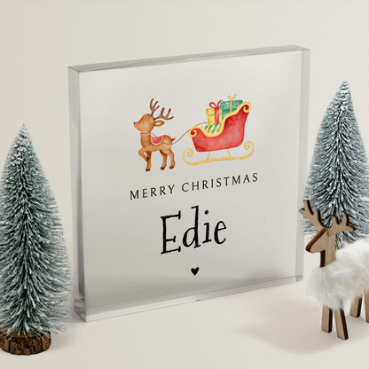 Framed Christmas-themed acrylic block with reindeer and sleigh, surrounded by decorative trees and deer figurines.
