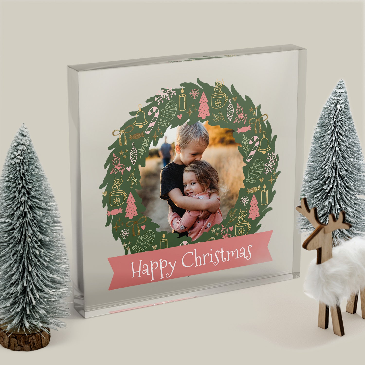 Framed photo of two children with a Christmas wreath design and 'Happy Christmas' text, surrounded by festive decorations.