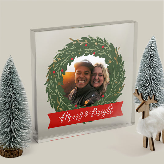 Framed holiday wreath with a couple's photo and 'Merry & Bright' text, surrounded by Christmas decor.