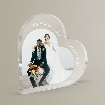 Heart-shaped acrylic photo block with a couple's wedding photo and personalized text on a beige background.