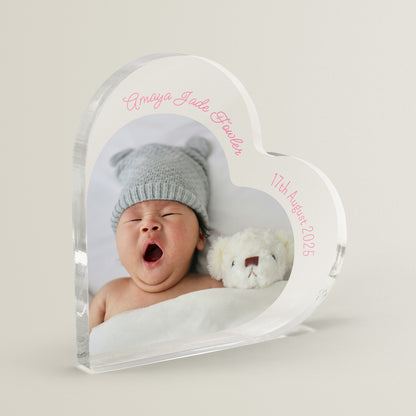 Heart-shaped acrylic photo block with a baby's picture, name, and date on a light gray background