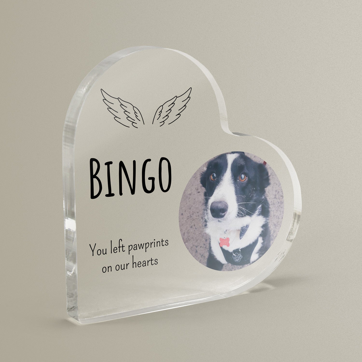 Heart-shaped acrylic block with a dog's photo, wings and text on a beige background.