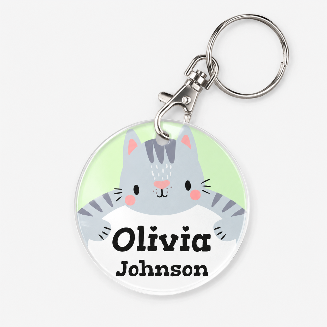 A personalised acrylic keychain featuring a cute cartoon gray tabby cat and example text 'Olivia Johnson'. 
