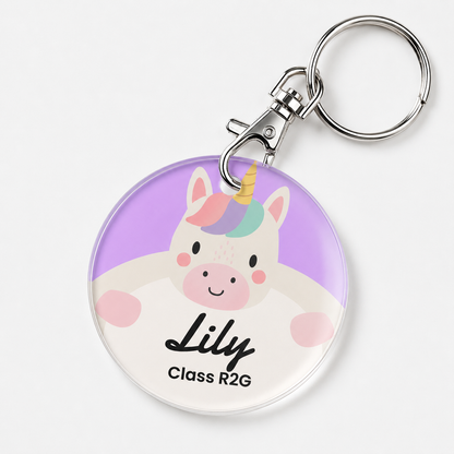 A custom acrylic keychain featuring a cute cartoon unicorn with a pastel rainbow mane and pink cheeks. The keychain is personalized with the name 'Lily' and 'Class R2G' in black text.