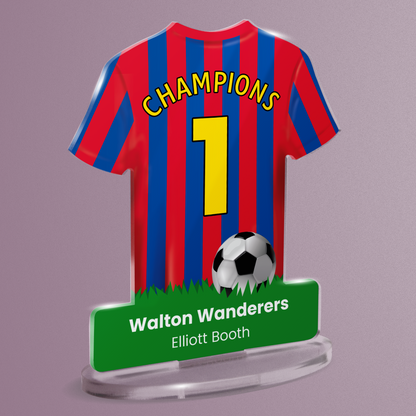 Acrylic t-shirt plaque with a red and blue striped sports shirt design with 'Champions' and number '1' on the shirt and the wording 'Walton Wanderers' 'Elliott Booth' on grass at the bottom of the plaque. Plaque is shown on a pale purple background.