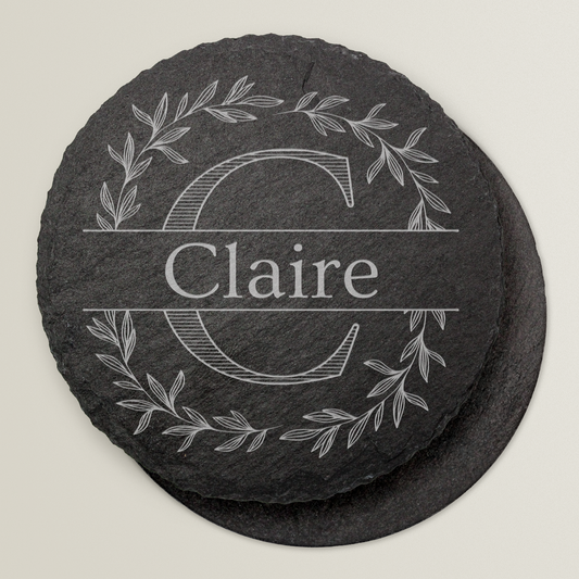 Round slate coaster with engraved name 'Claire' and decorative elements on a light grey background