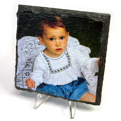Slate photo plaque with a photo of young child wearing a white blouse and blue shorts on a stand.