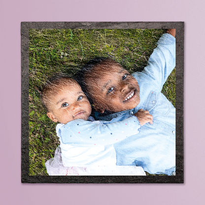 Photo of two children hugging on grass printed onto a slate coaster.