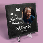 Slate coaster on a stand with printed photo of a woman with message In Loving Memory, Susan, 1945-2025 in white text