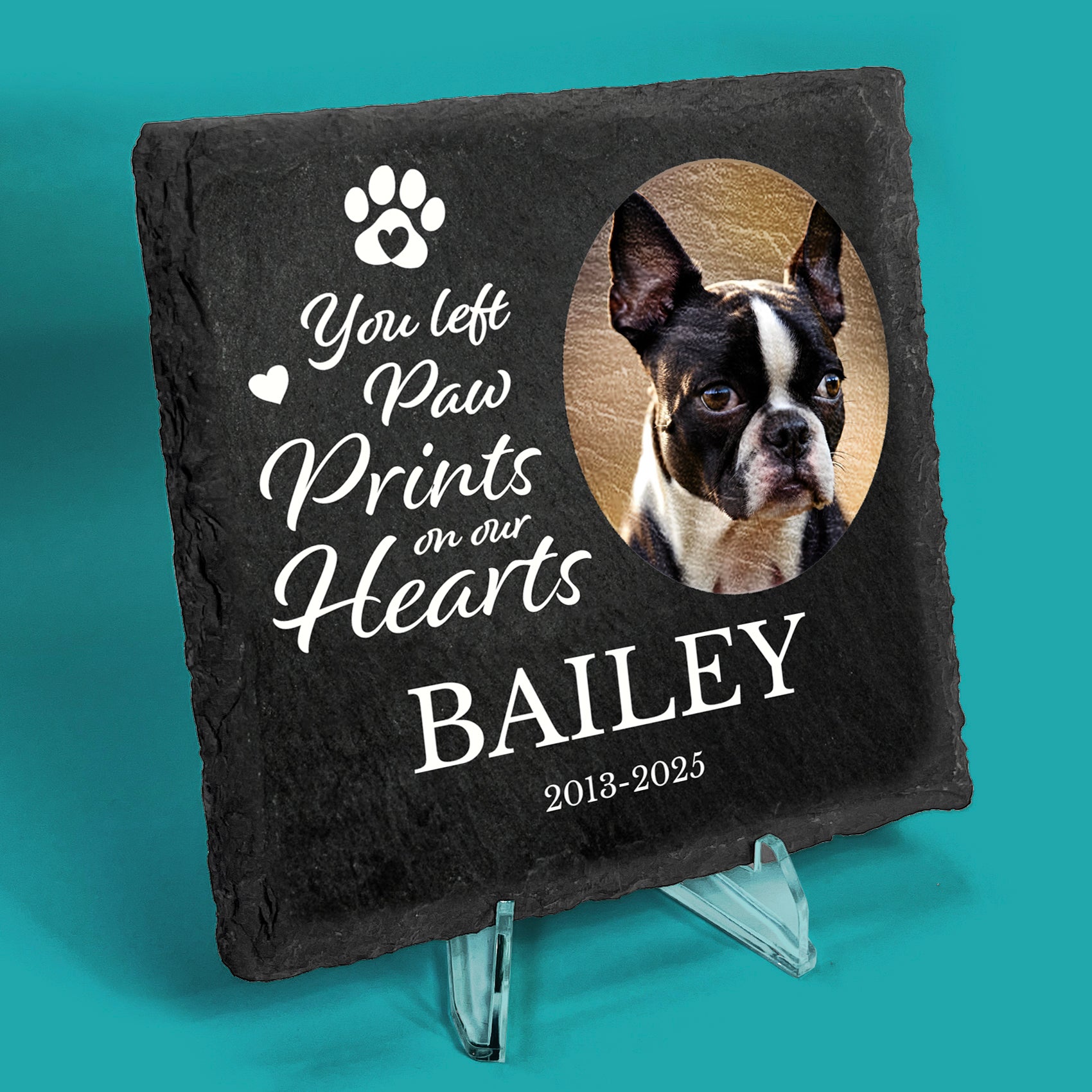 Slate coaster on a stand with printed photo of a dog with message You left paw prints on our hearts, Bailey, 2013-2025 in white text