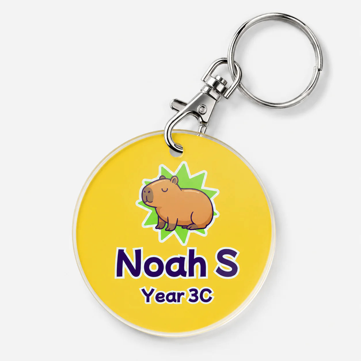 A personalised acrylic keychain featuring a yellow circular tag with a cartoon capybara, the name 'Noah S' in purple, and 'Year 3C' below it.